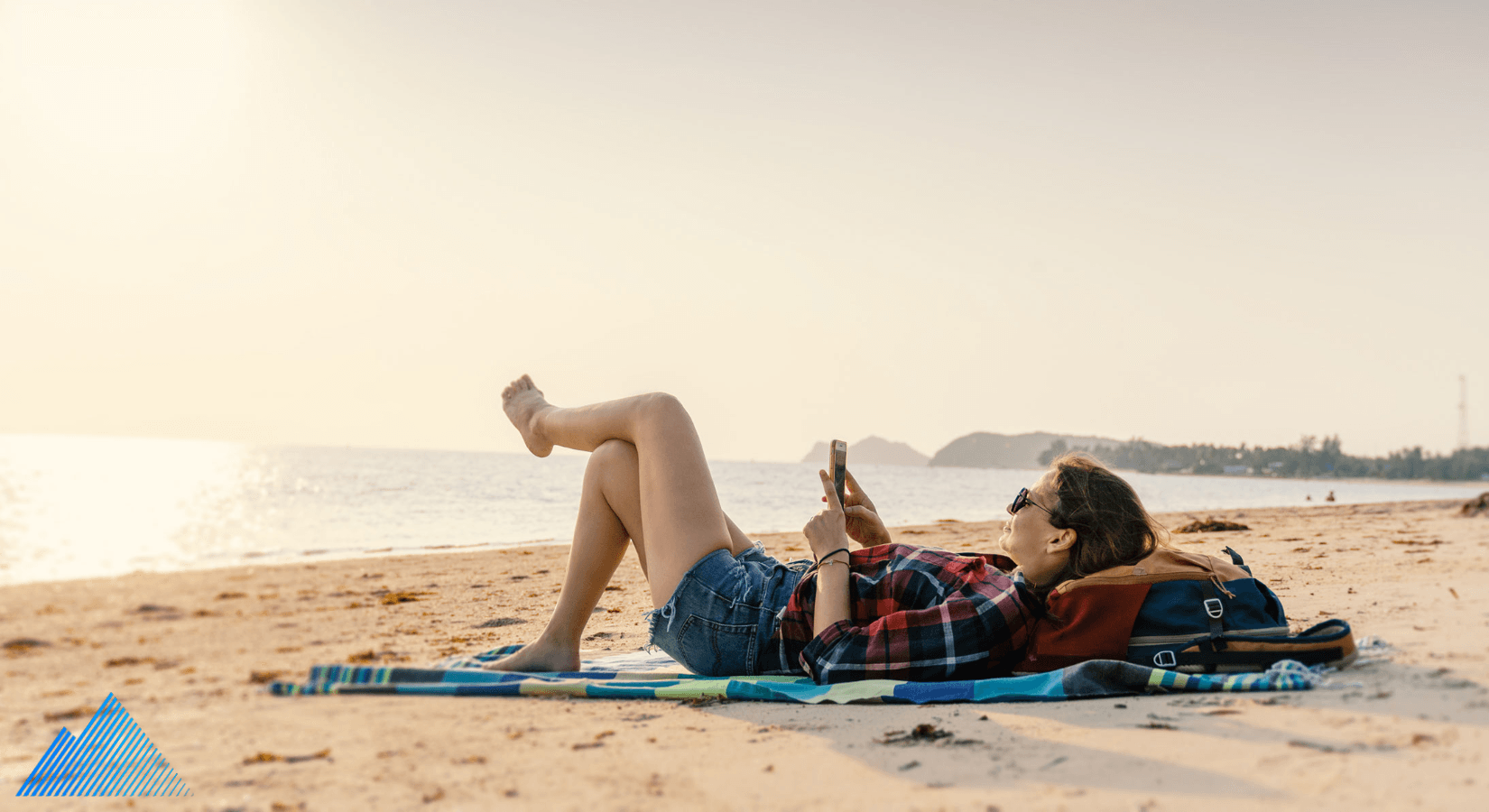 Woman laying on the beach looking at her phone