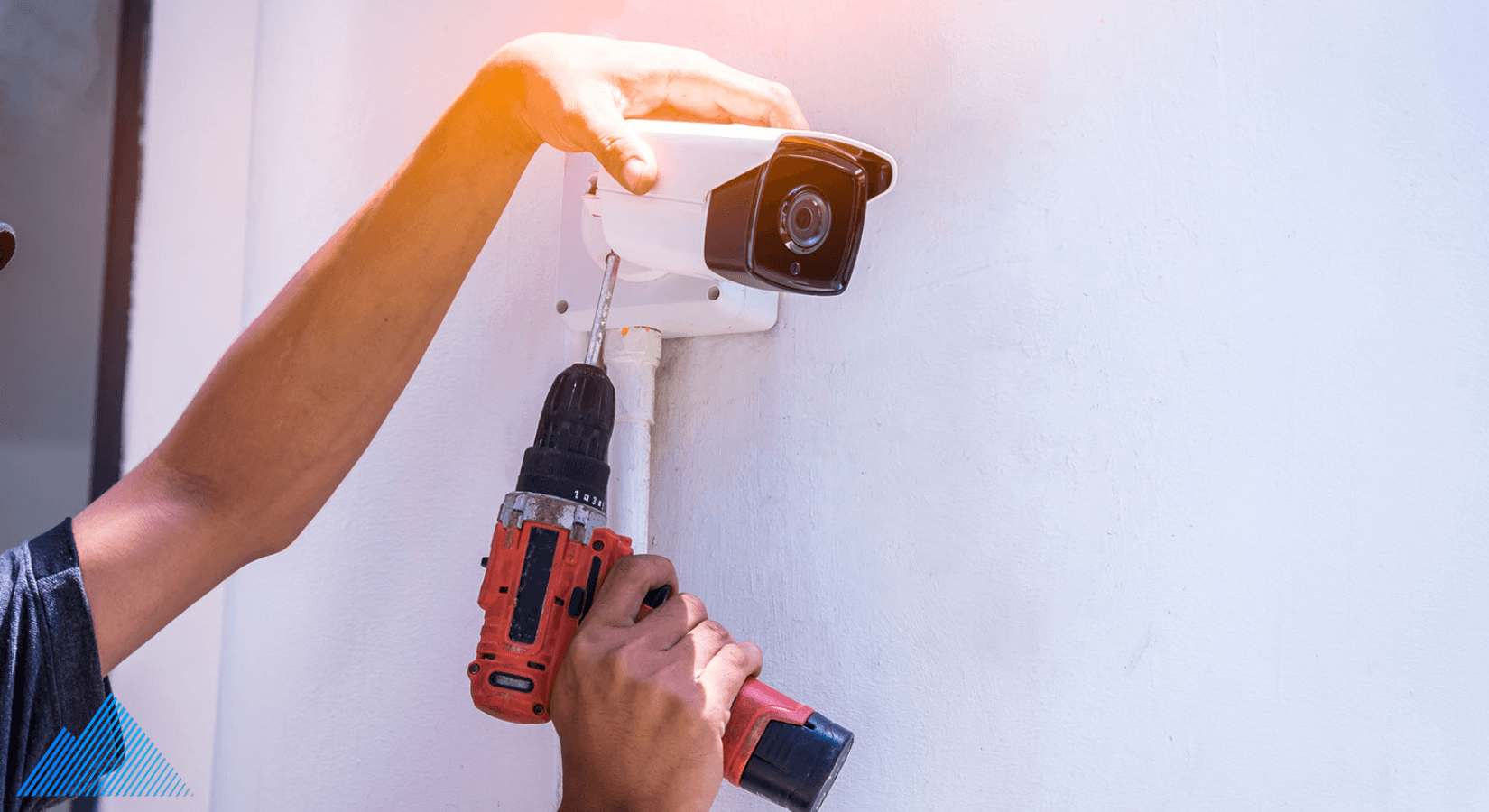 Person installing a security camera outdoors with a drill