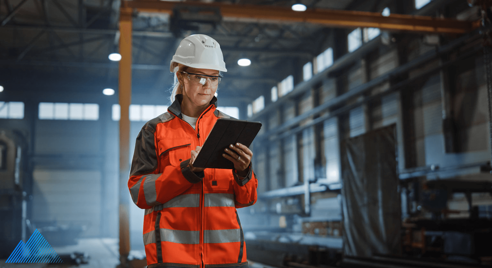Woman in orange safety vest and hard hat using a tablet