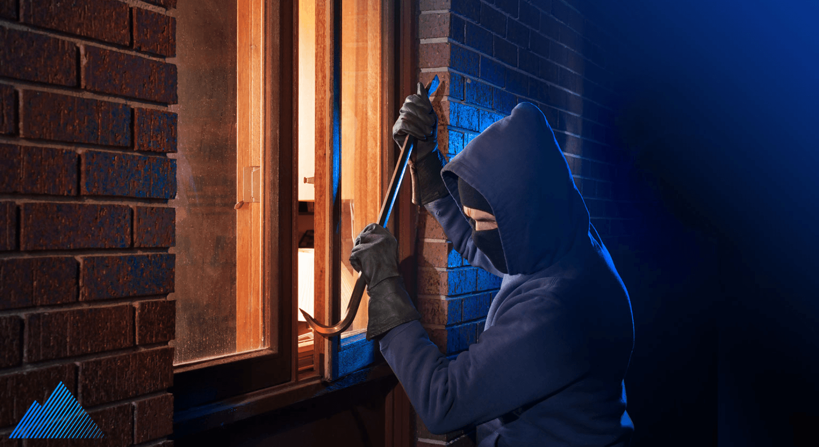 Masked person trying to break into a building with a crowbar