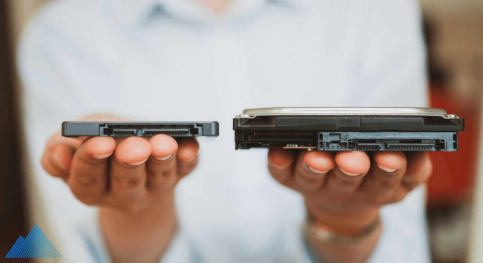 Person holding two different sized hard drives