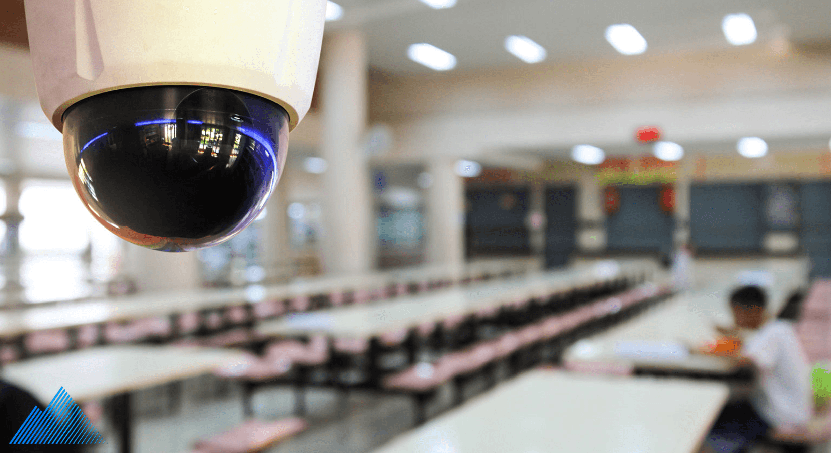 Dome security camera mounted on ceiling in a school cafeteria